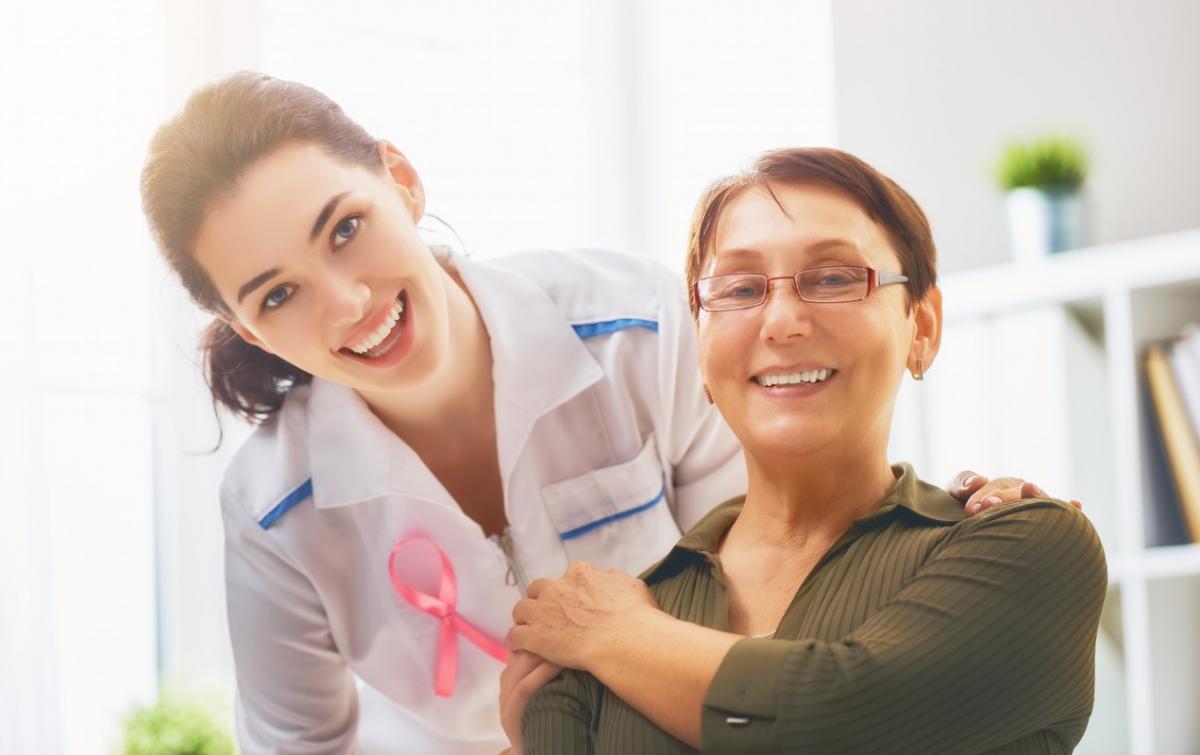 female patient listening to doctor against pink awareness ribbon