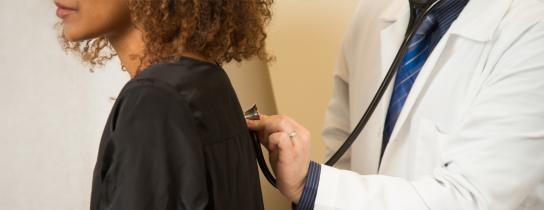 Healthcare provider using stethoscope on patient's back