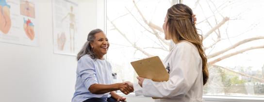 Female healthcare provider shaking hands with smiling woman patient