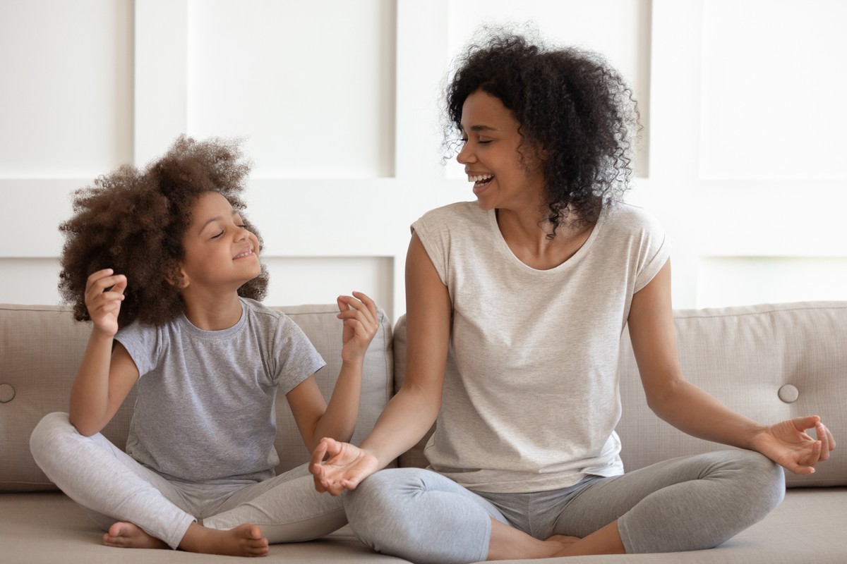 african american woman teaching cute little adorable daughter meditating