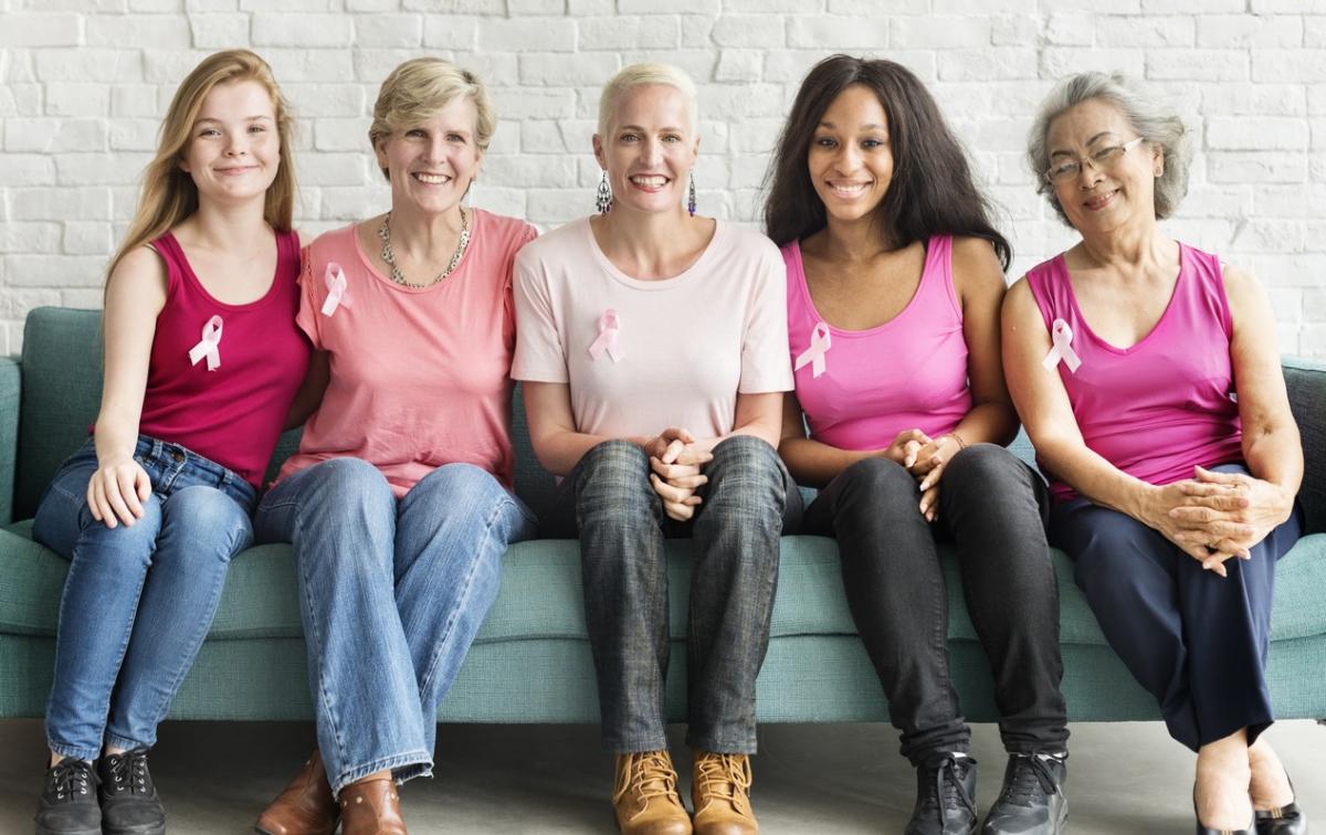 beautiful women of different ages with pink ribbons sitting on sofa in room