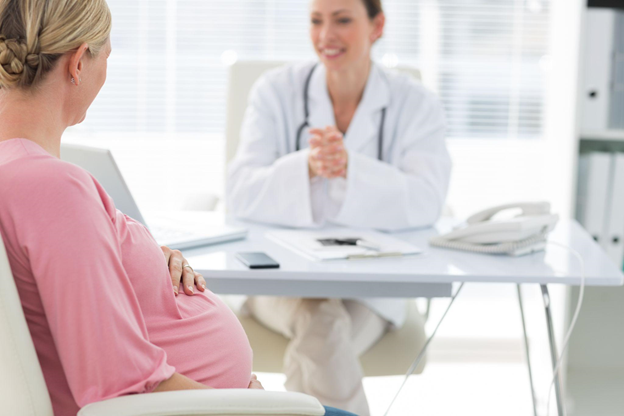 Side view of expectant woman consulting female doctor in clinic
