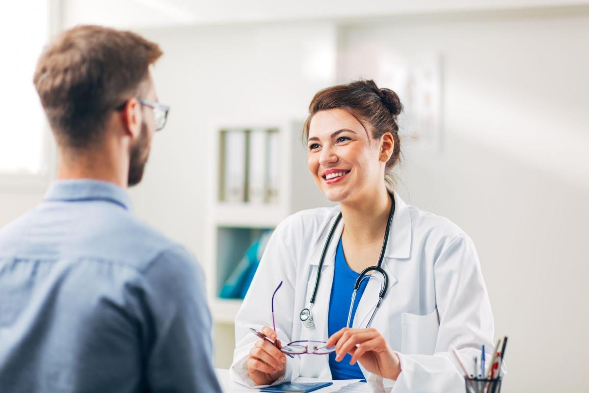 Female doctor sitting in her medical office with stethoscope talking to patient