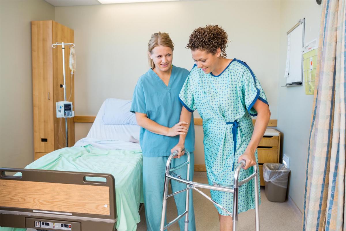 female nurse helping patient to walk using walker