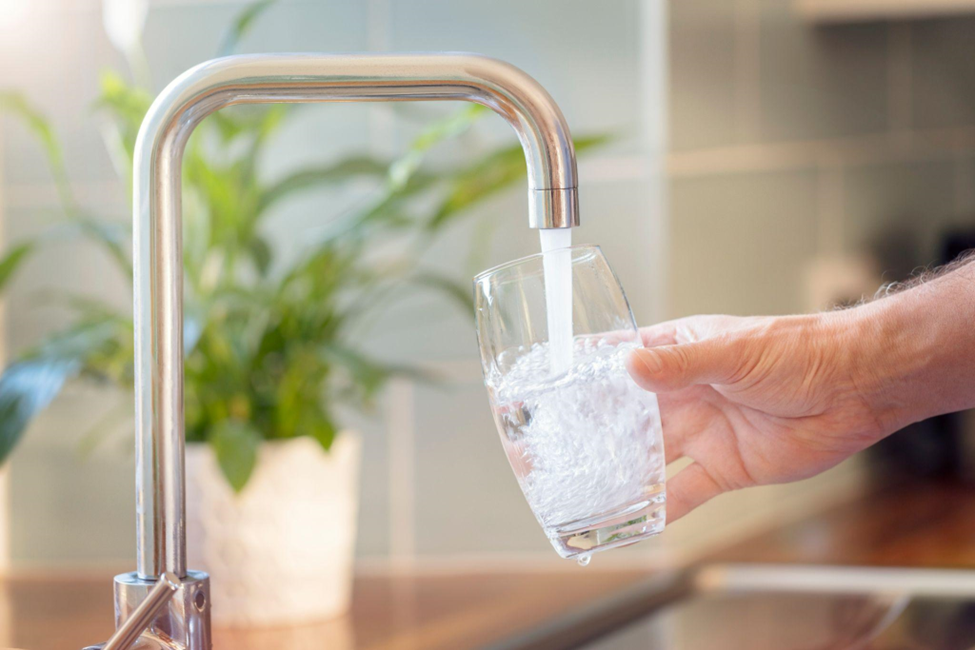 Filling up a glass with clean drinking water from kitchen faucet