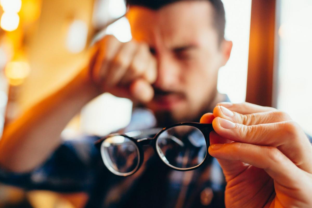 guy is holding his eyeglasses in one hand and rubbing his eyes with another hand.