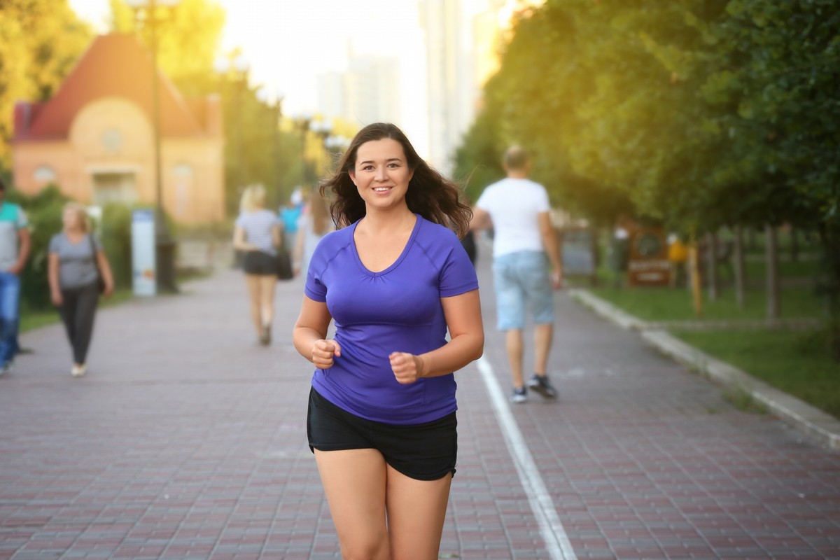 Overweight young woman jogging in the street