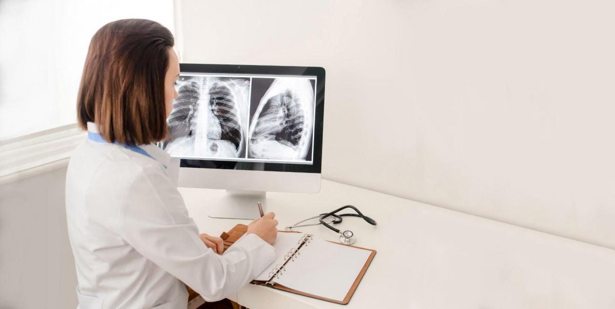Radiologist doctor analysis pulmonary x-ray and make a medical description of xray in notebook