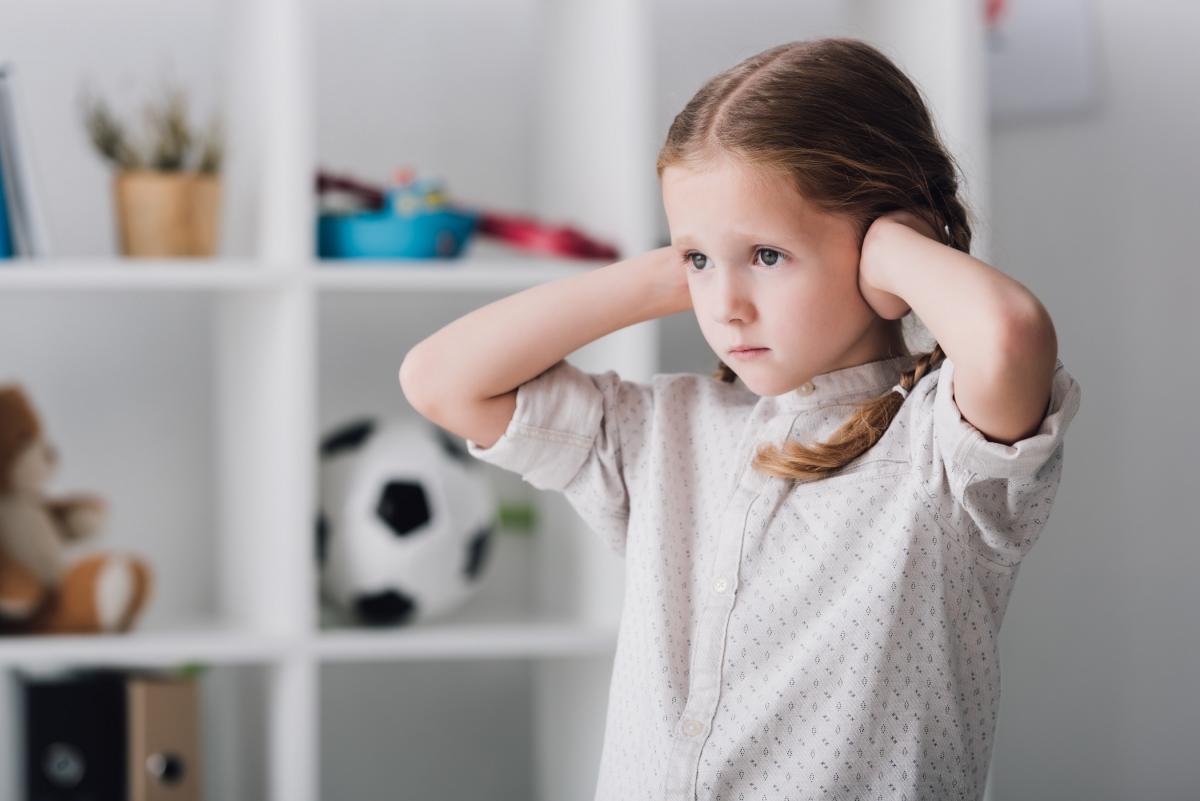 sad little child covering ears with hands