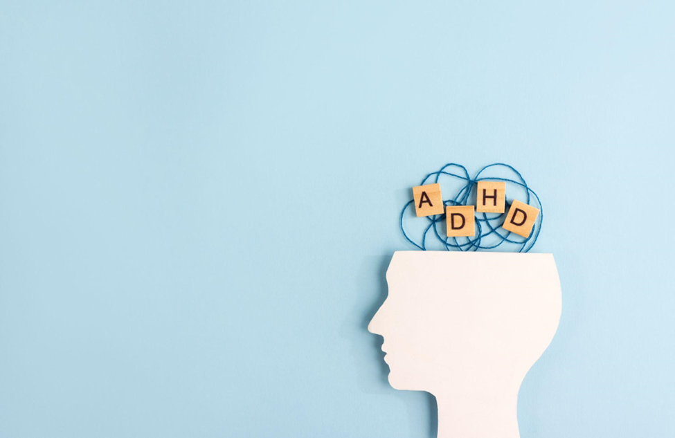Silhouette of human head and wooden blocks with the letters ADHD on pastel background