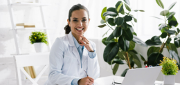 happy-nutritionist-in-white-coat-near-vegetables-and-laptop