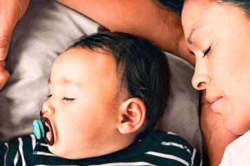 Parent rests alongside their baby