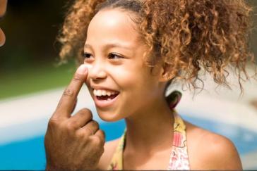 dad applying sunburn to girl's nose