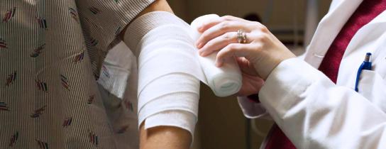 Healthcare provider bandaging patient's arm
