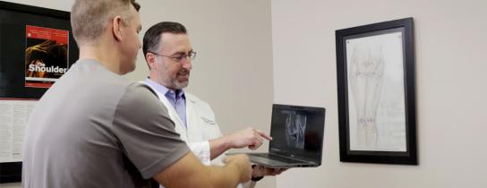 Physician and patient reviewing x-ray imaging on a laptop