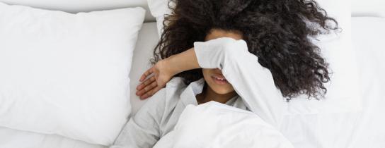 Woman in bed with her arm covering her face