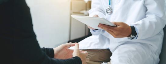 Healthcare provider with clipboard speaking with patient