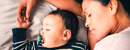 Parent rests alongside their baby