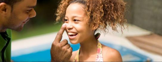 dad applying sunburn to girl's nose