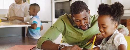 Father and daughter doing homework in kitchen