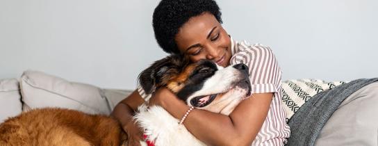 Woman hugging dog on couch