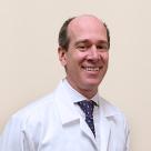 A photo of Michael Angeline, MD smiling in a lab coat