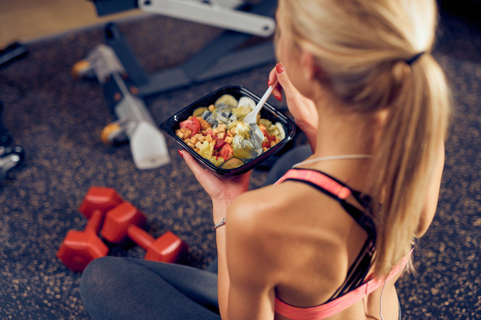 Top view of woman eating healthy food while sitting in a gym