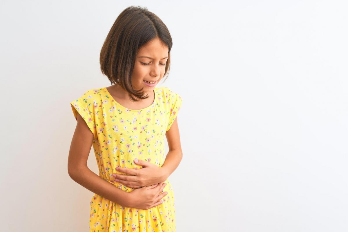 Young child girl hand on stomach because indigestion, painful illness feeling unwell.