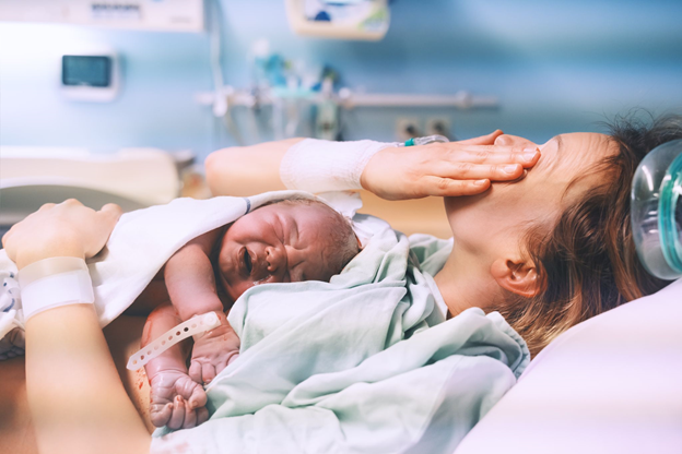 Young mom hugging her newborn baby after delivery